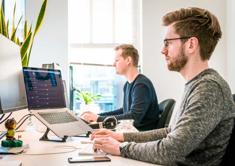 deux personnes en train de coder sur une table